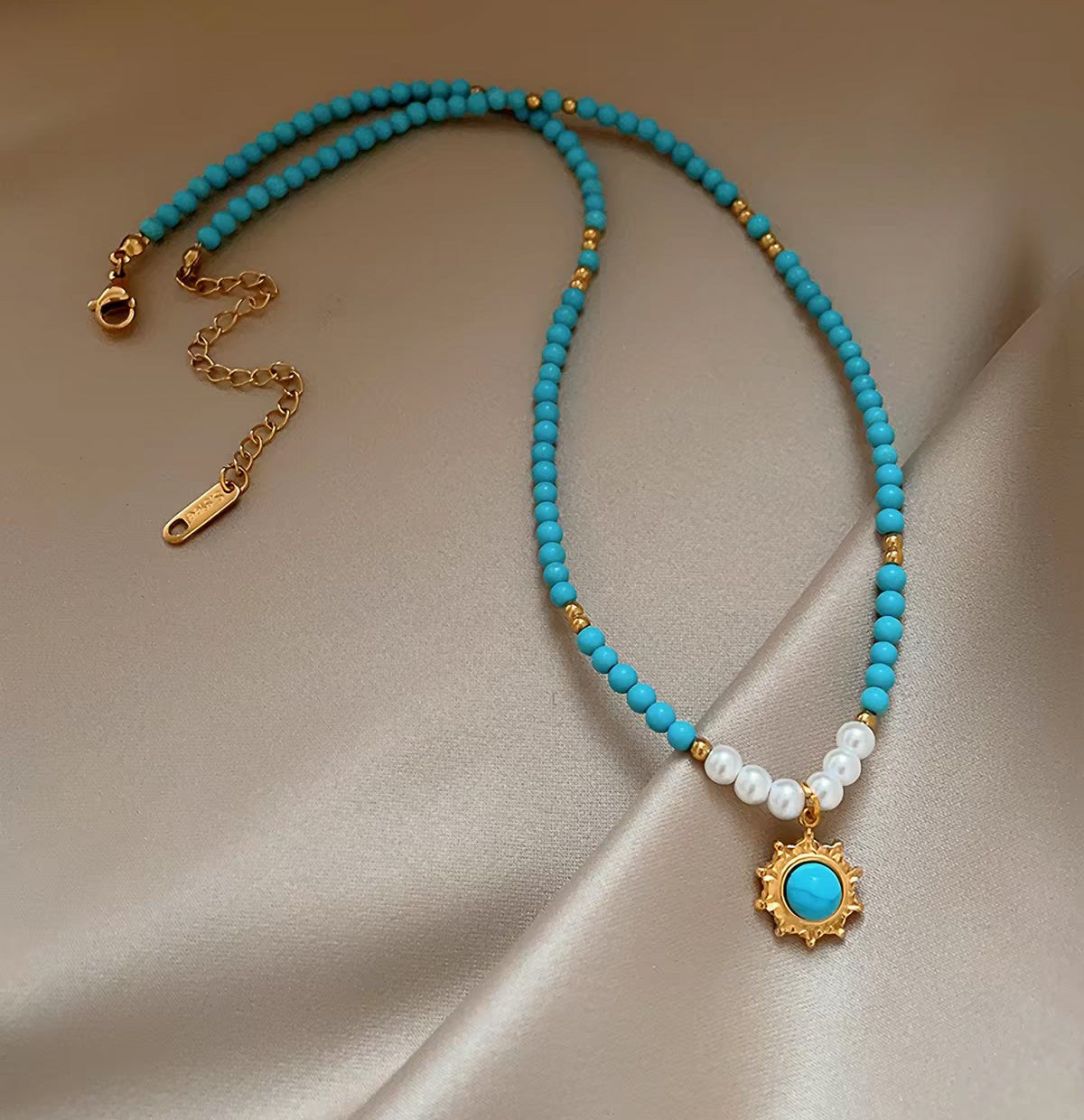 Full view of turquoise bead and pearl strand necklace with gold-plated extender chain