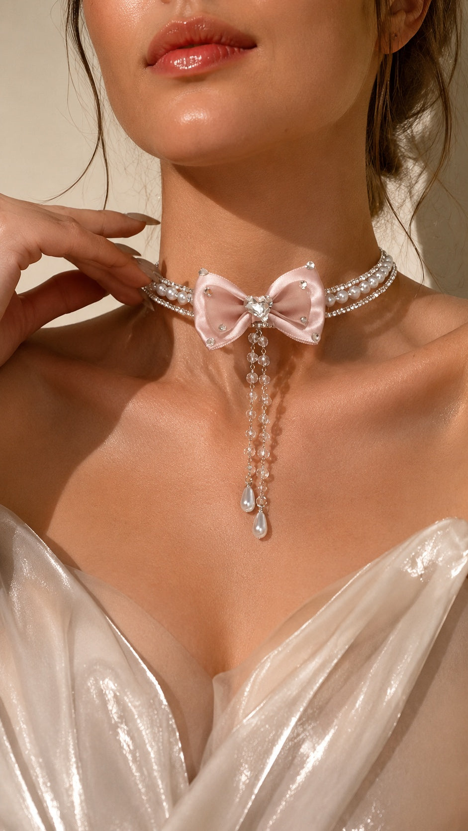 Close up of model wearing romantic blush pink satin bow pearl choker with cascading dangles