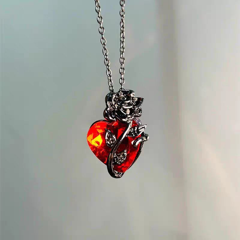 High-definition detail of vibrant red crystal heart encased in black sculpted rose leaves and stem