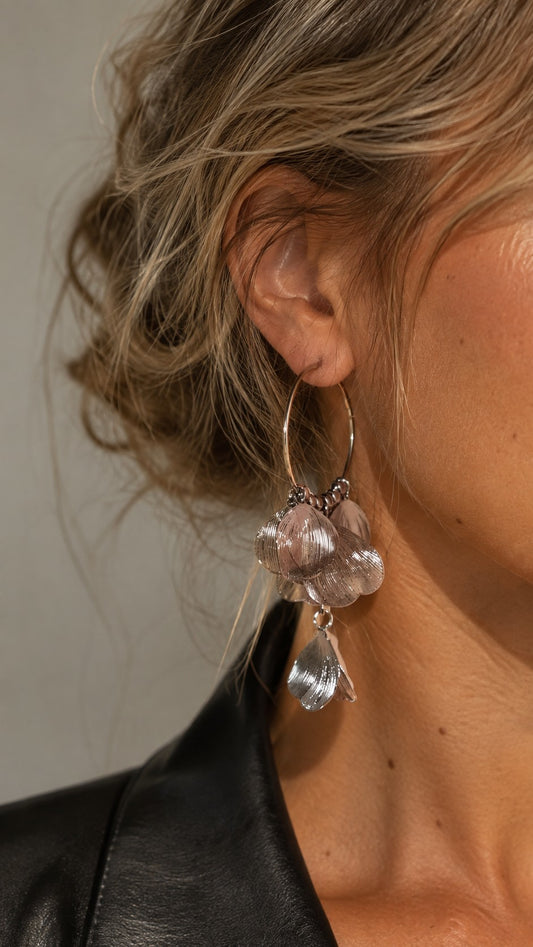 Close-up of a blonde model wearing silver textured petal tassel hoop earrings paired with a black leather jacket.