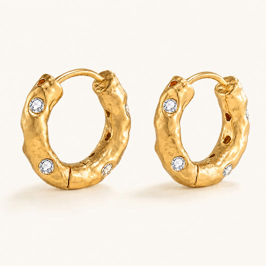 Minimalist display of 18K gold-plated chunky hoop earrings featuring a unique hammered texture and cubic zirconia on a white background.