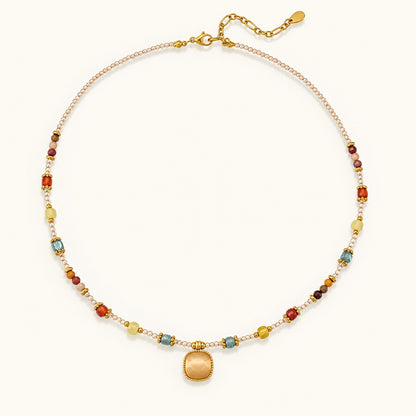 Flatlay view of a colorful beaded gemstone necklace with a gold cushion-cut pendant and 18K gold-plated titanium steel chain.