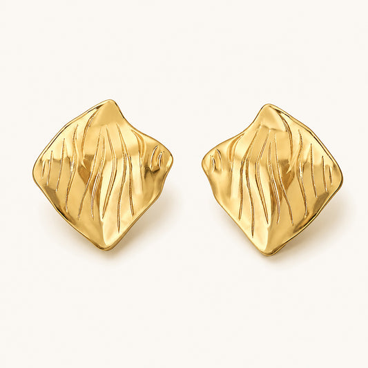 Minimalist flat lay of 18K gold-plated square stud earrings featuring an artistic crinkled surface on a clean white background.