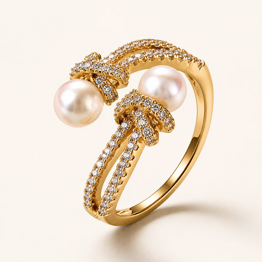 Detailed macro close-up of an 18K gold-plated adjustable ring showing intricate micro-paved zircon knots and two freshwater pearls.