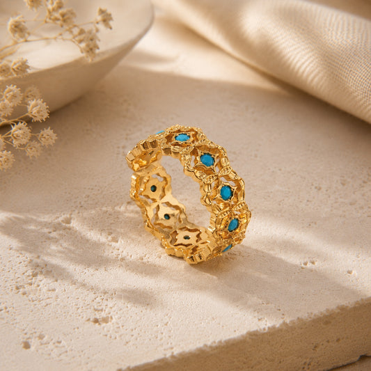 Intricate 18K gold-tone filigree ring with turquoise beads and zirconia accents displayed elegantly on a warm aesthetic stone.