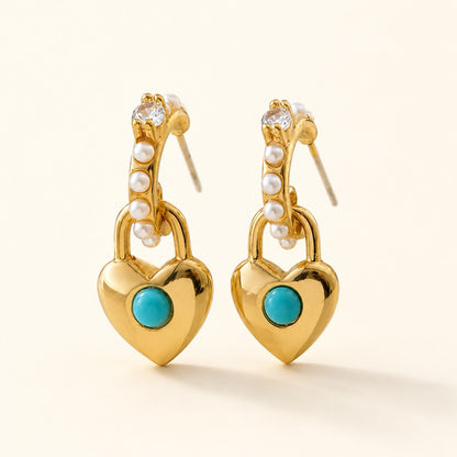 Pair of 18k gold plated turquoise heart lock drop earrings with micro pearls on cream background