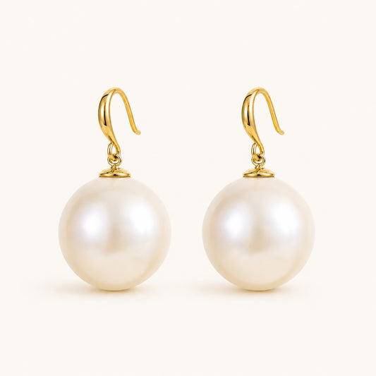 Minimalist flat lay of 14K gold-plated french hook earrings featuring massive 19mm statement pearls on a white background.