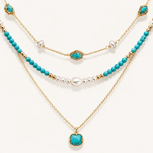 Detailed flat lay of a three-tier 22K gold-plated necklace featuring vibrant turquoise beads, genuine pearls, and a turquoise pendant on a white background.