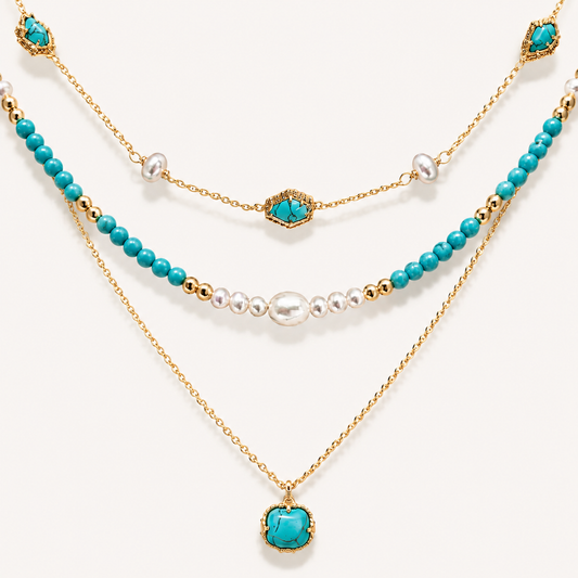 Detailed flat lay of a three-tier 22K gold-plated necklace featuring vibrant turquoise beads, genuine pearls, and a turquoise pendant on a white background.