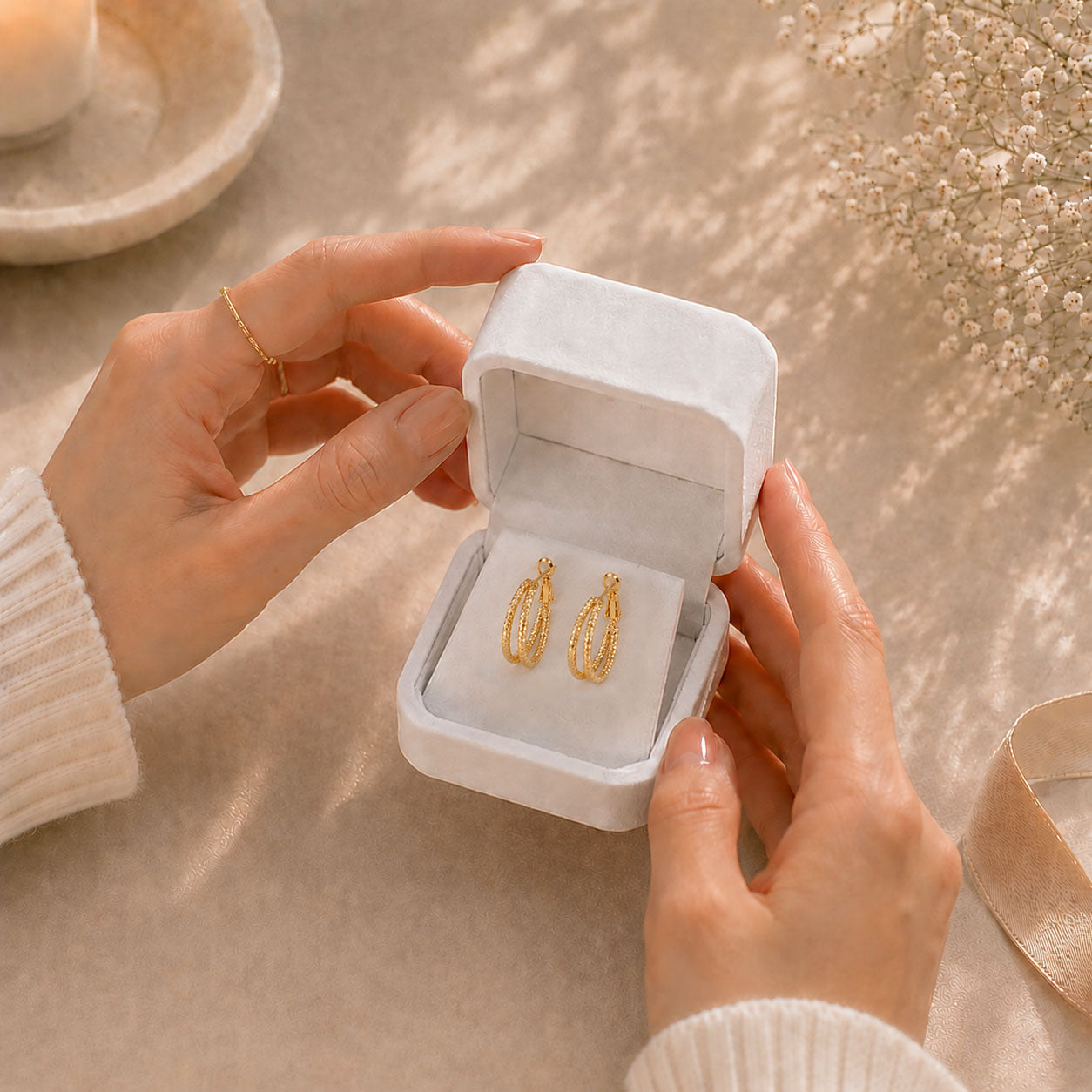 Hands gently opening a premium white Moonlook gift box revealing everyday hoop earrings.