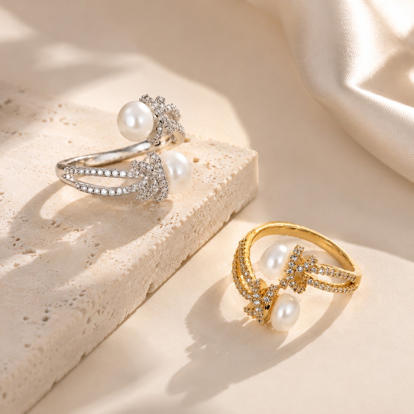 Beautiful display comparing adjustable freshwater pearl and zircon knot rings in both 18K gold-tone and white gold-tone on a textured aesthetic stone.