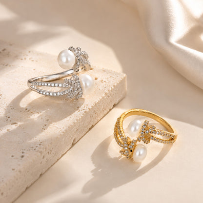 Beautiful display comparing adjustable freshwater pearl and zircon knot rings in both 18K gold-tone and white gold-tone on a textured aesthetic stone.