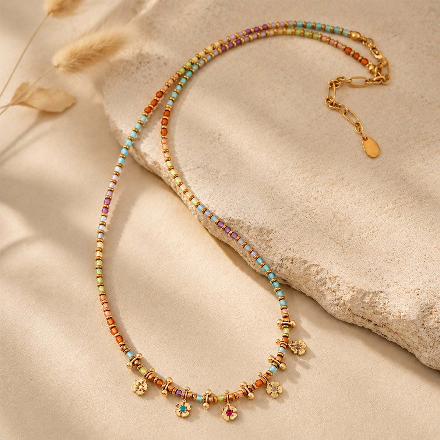 Boho-chic colorful beaded necklace draped elegantly over a textured stone in warm sunlight.