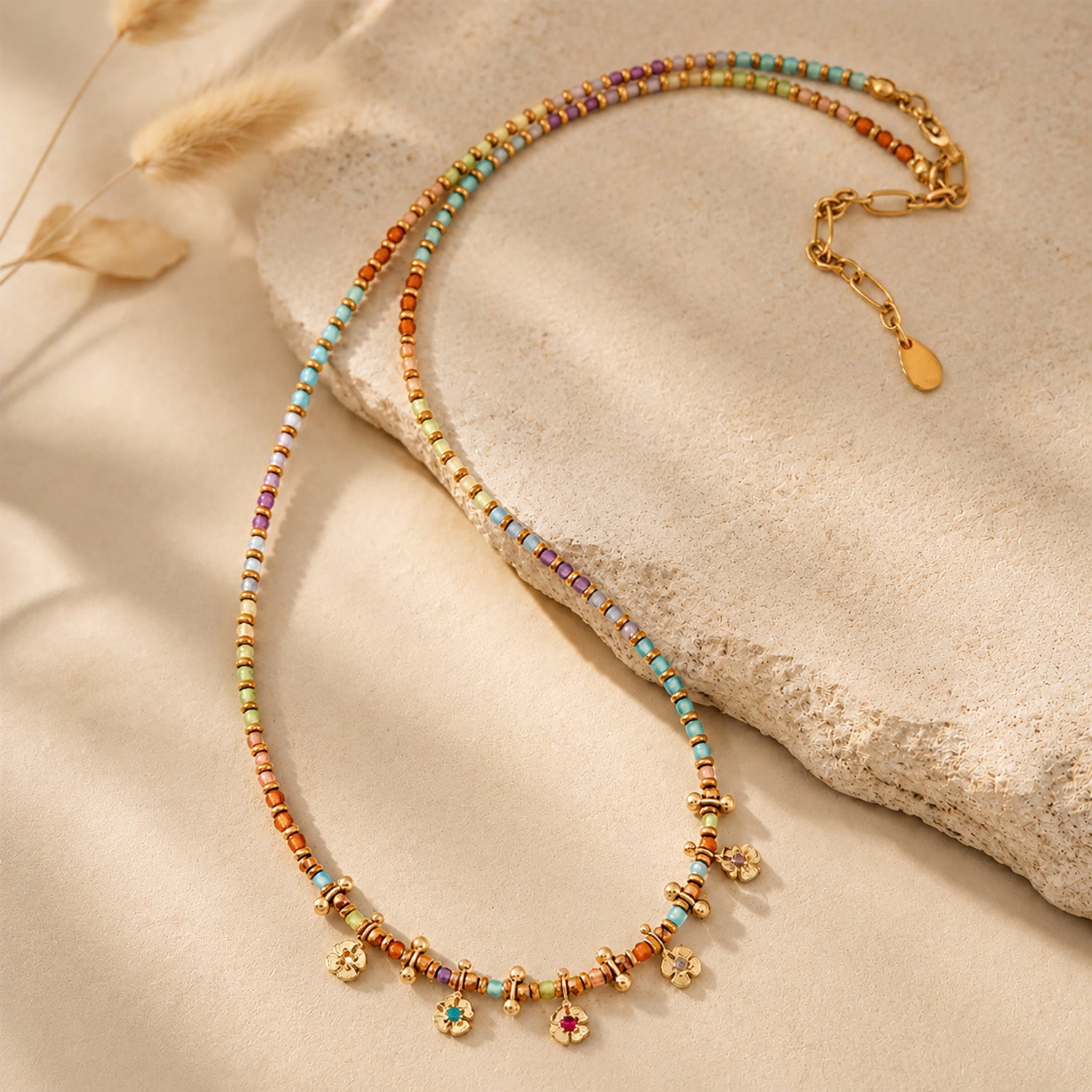 Boho-chic colorful beaded necklace draped elegantly over a textured stone in warm sunlight.