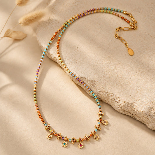 Boho-chic colorful beaded necklace draped elegantly over a textured stone in warm sunlight.