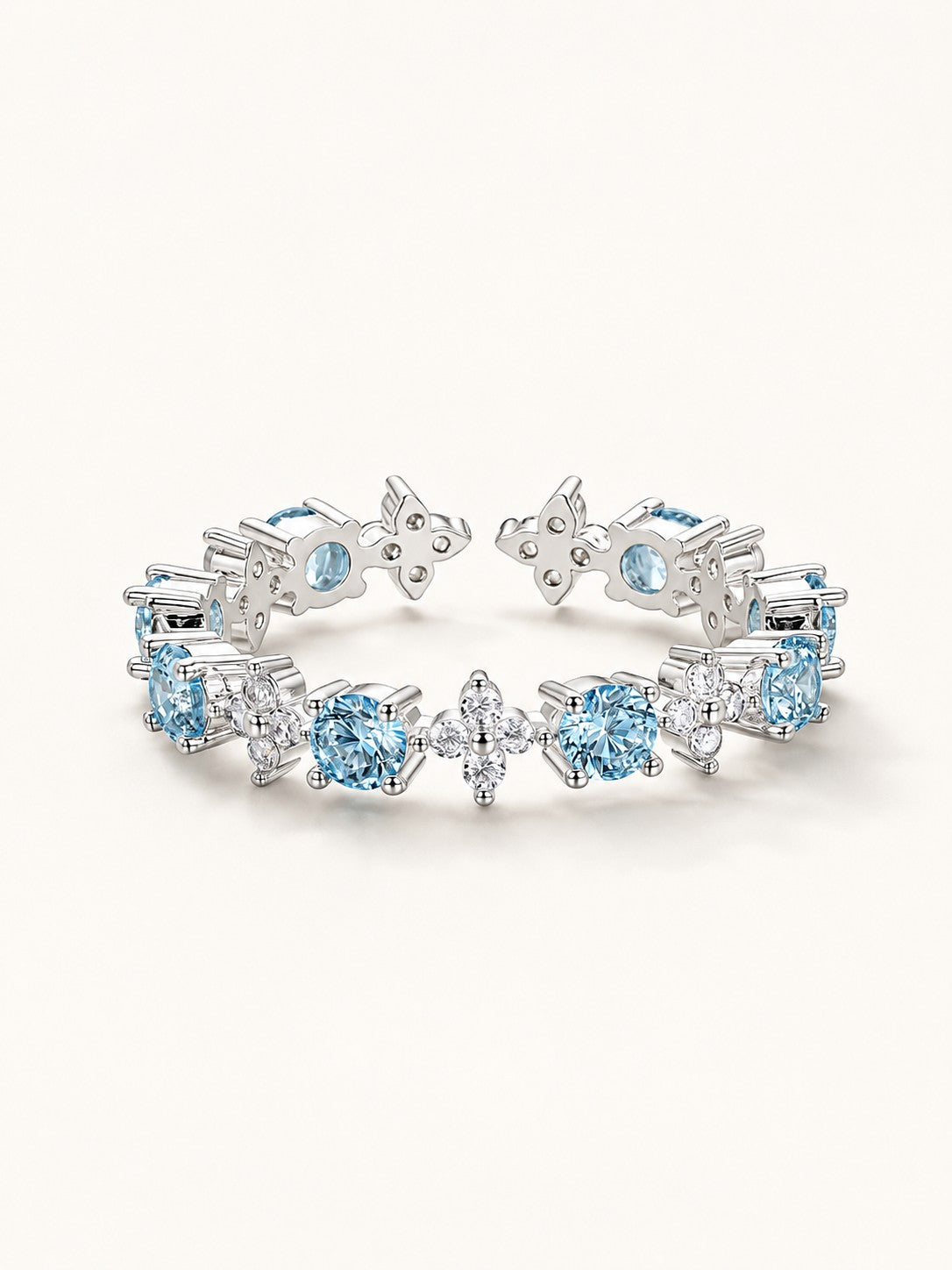 Platinum plated open ring featuring alternating clear and ocean blue cubic zirconia in four-leaf floral shapes