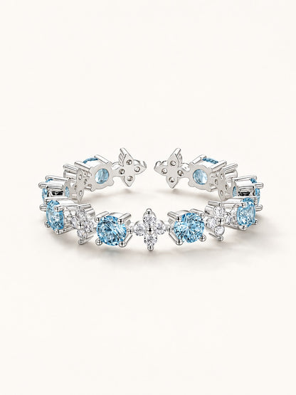Platinum plated open ring featuring alternating clear and ocean blue cubic zirconia in four-leaf floral shapes