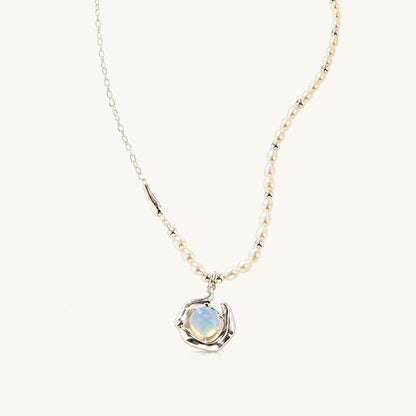 Flatlay view of asymmetric freshwater pearl necklace with silver chain and molten fluid opaline pendant