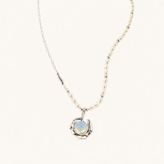 Flatlay view of asymmetric freshwater pearl necklace with silver chain and molten fluid opaline pendant