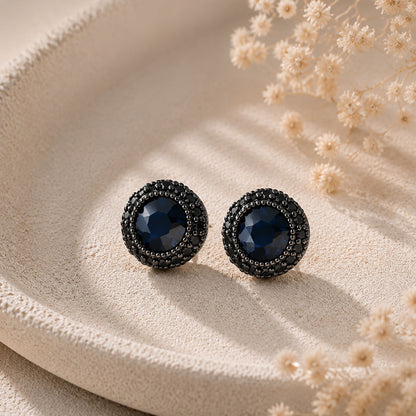 Close-up of bold black round zirconia stud earrings resting in a minimalist stone tray.