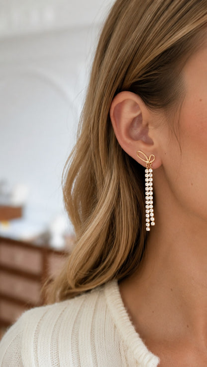 Close up of brunette model showcasing 7cm long rhinestone tassel bow earrings catching light
