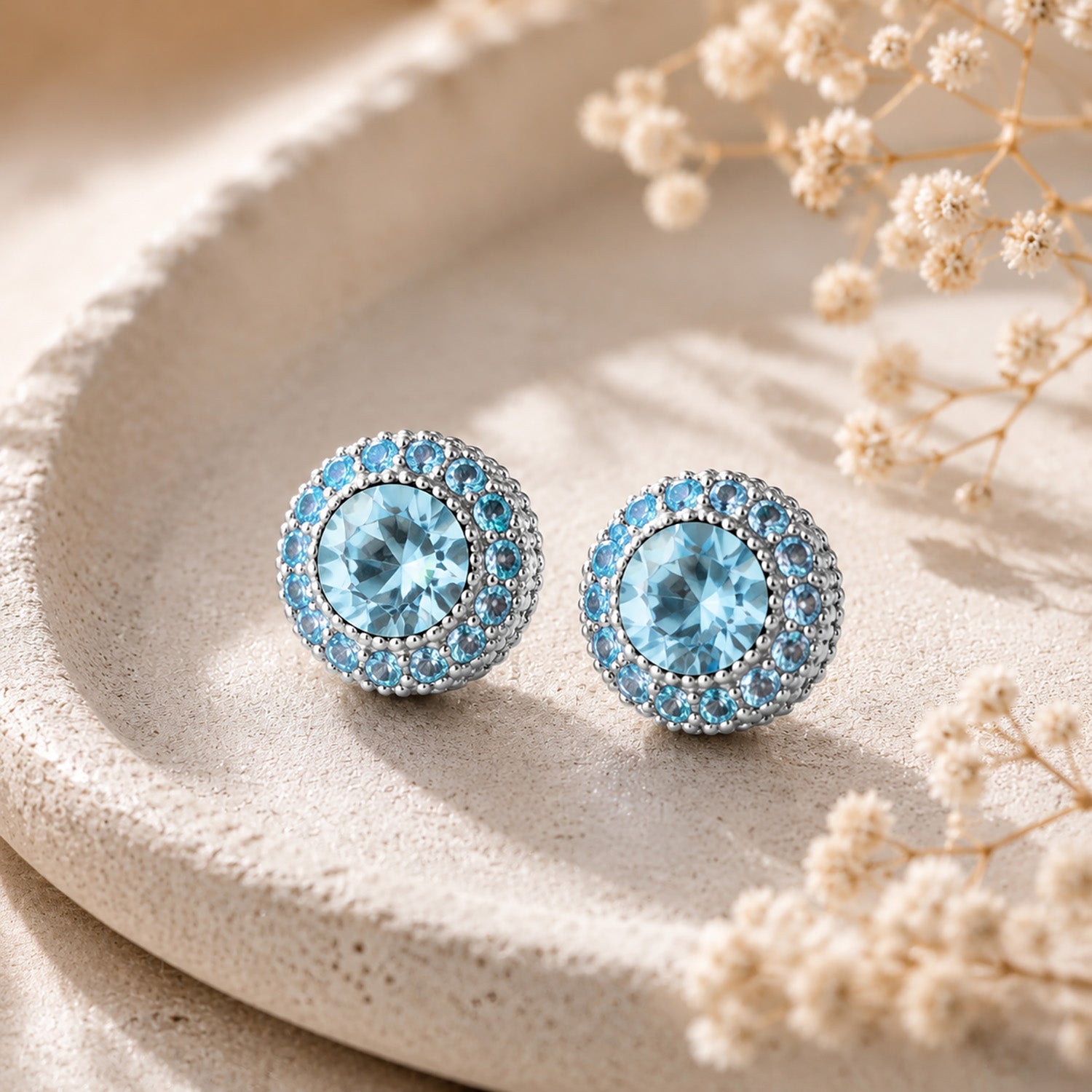 Close-up of elegant blue round zirconia stud earrings resting in a minimalist stone tray.