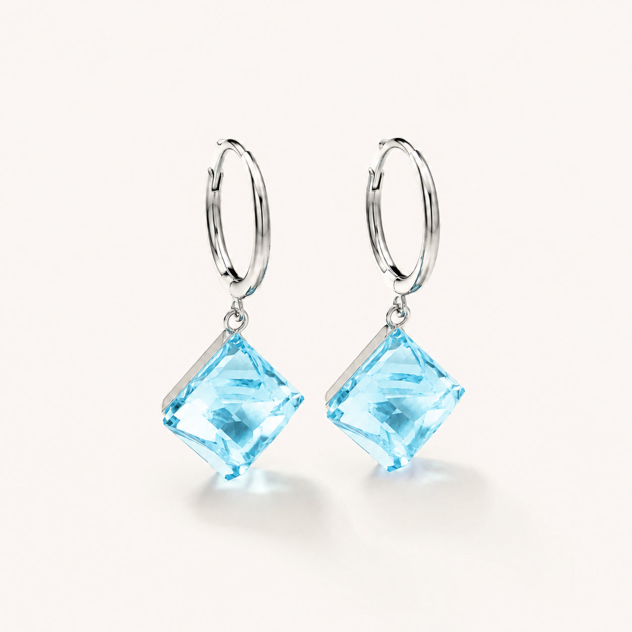 Minimalist white gold-tone hoop earrings with square ocean blue zirconia pendants on a clean white background.