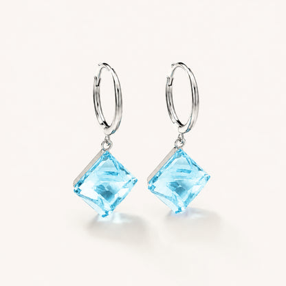 Minimalist white gold-tone hoop earrings with square ocean blue zirconia pendants on a clean white background.