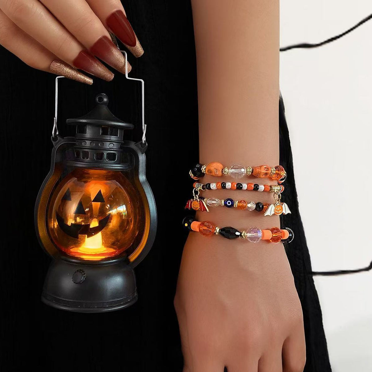 Close-up of model wrist with spooky season Halloween beaded bracelet stack and pumpkin lantern