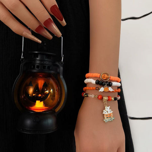 Model wearing orange and black Halloween stackable clay bead bracelets holding a glowing jack-o-lantern