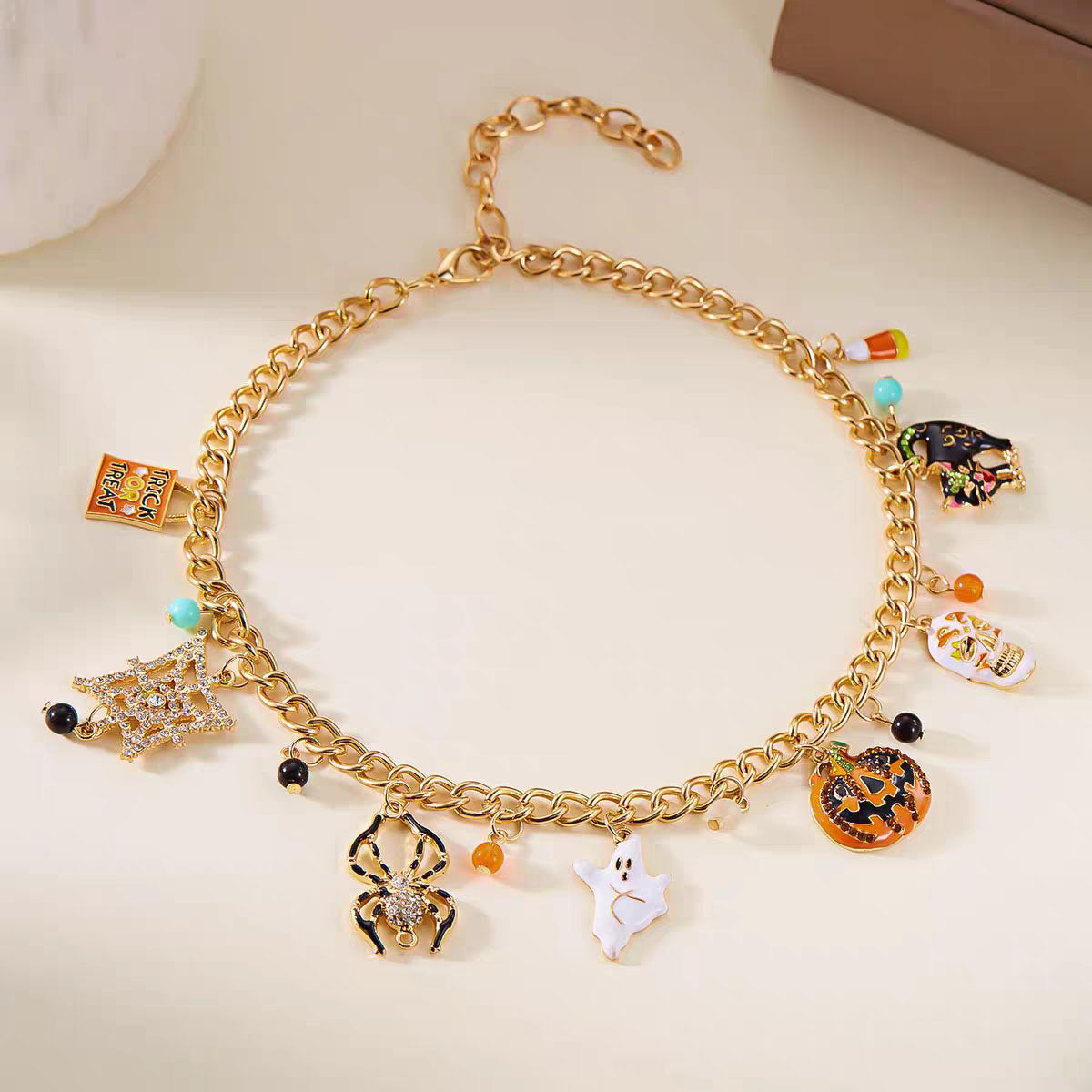 Gold chain Halloween charm bracelet with enamel pumpkin, ghost, rhinestone spider, and candy corn charms