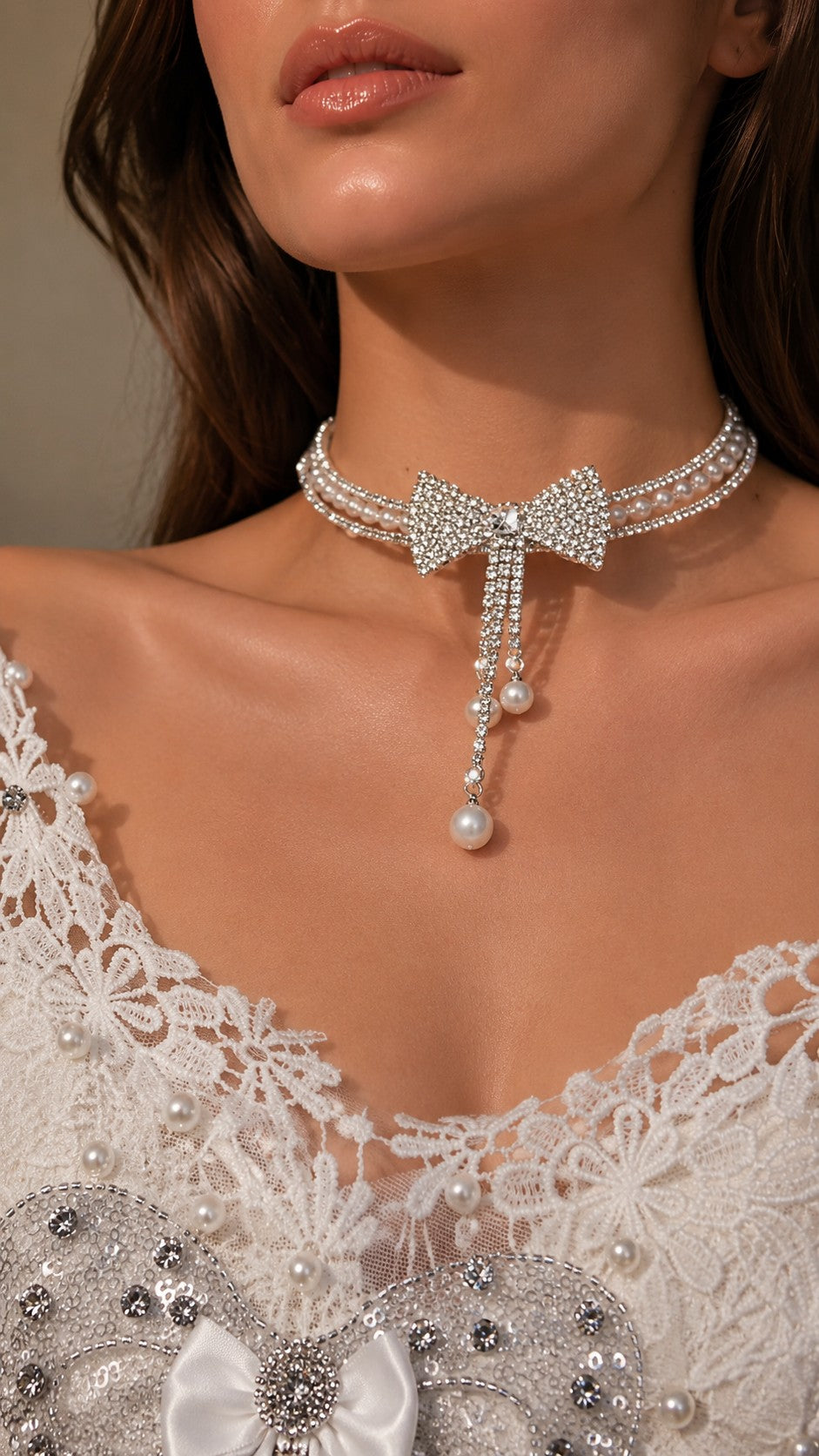 Close up of model wearing full rhinestone bow pearl choker with cascading tassels and lace wedding dress