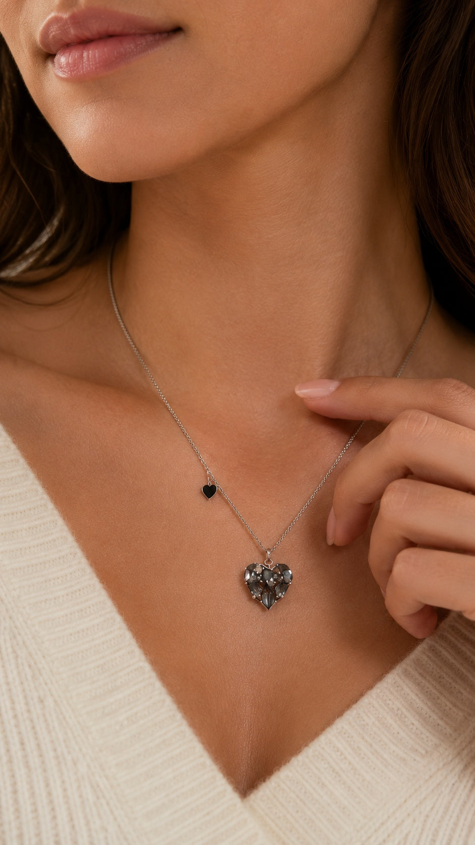 Close up of model touching collarbone showing black CZ heart pendant necklace with side charm accent