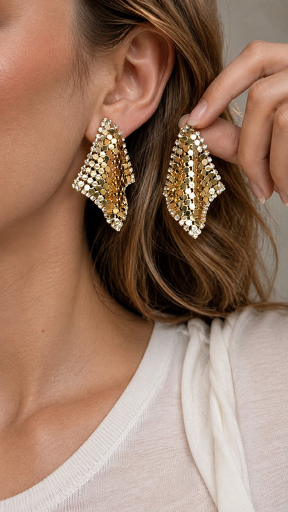 Model holding up a sparkling 4.3cm gold liquid metal mesh scarf stud earring next to ear