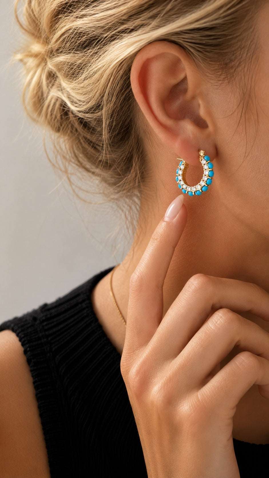 Model touching neck showcasing 2cm turquoise and pave crystal gold hoop earrings with black top