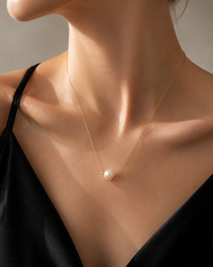 Close up of a classic single aurora pearl pendant resting gracefully on the collarbone.