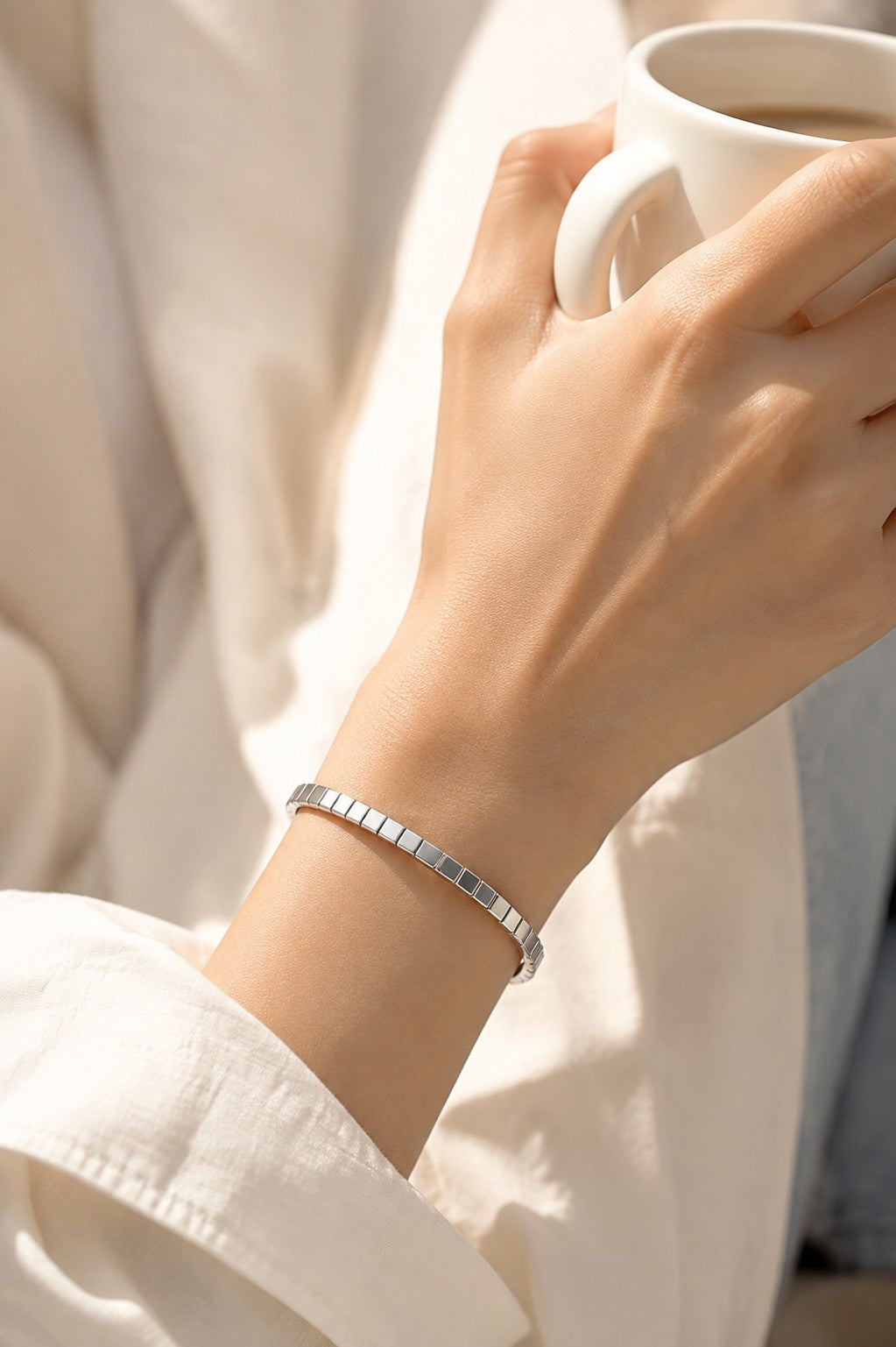 Model holding white coffee mug showcasing silver ice cube square link bracelet with white shirt sleeve