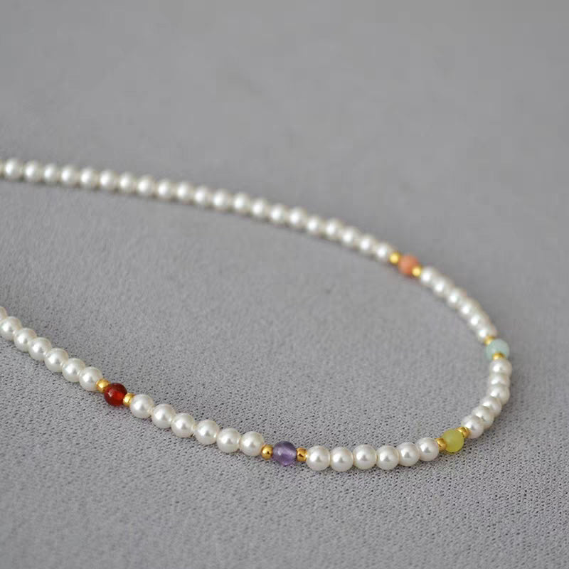 Detailed close-up of multi-colored accent beads spaced along luminous white pearl strand