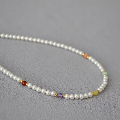 Detailed close-up of multi-colored accent beads spaced along luminous white pearl strand