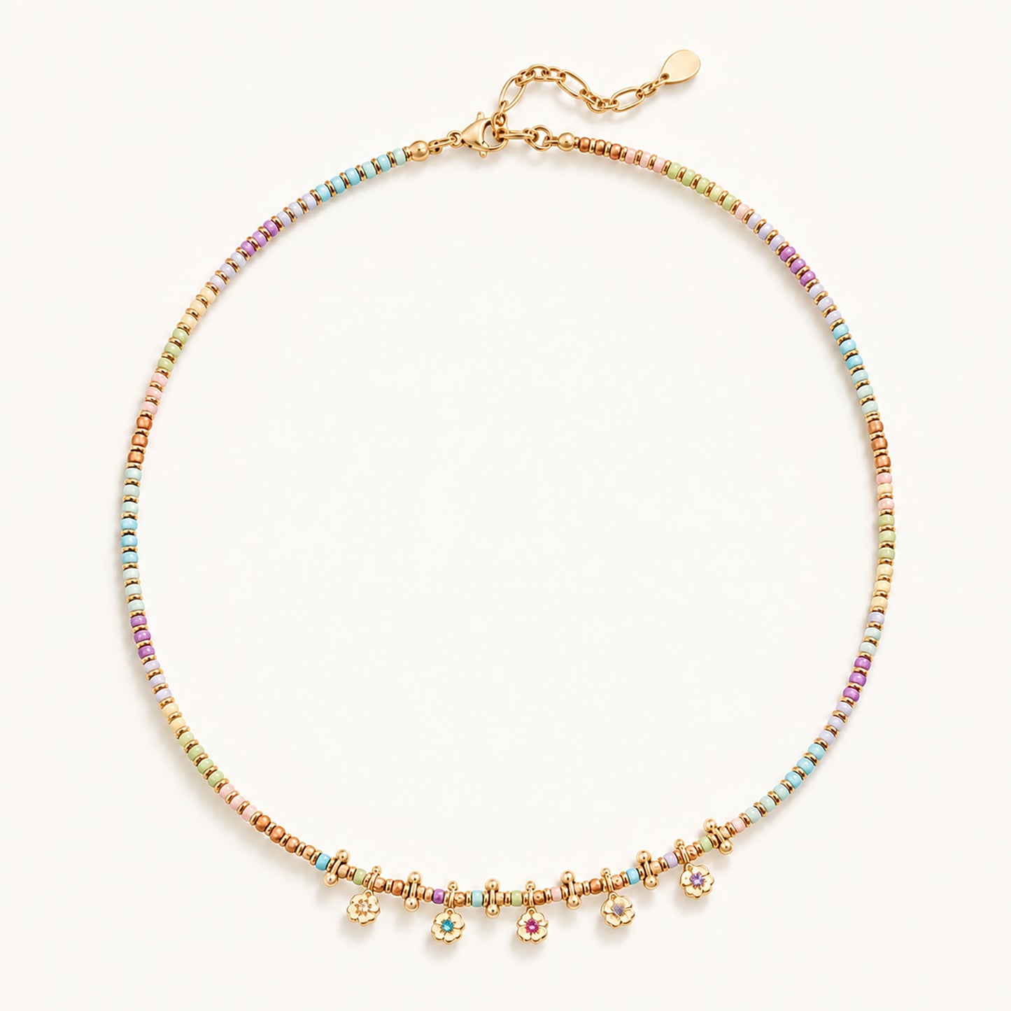 Minimalist flat lay of a gold-tone beaded necklace featuring natural stones and dainty floral pendants.