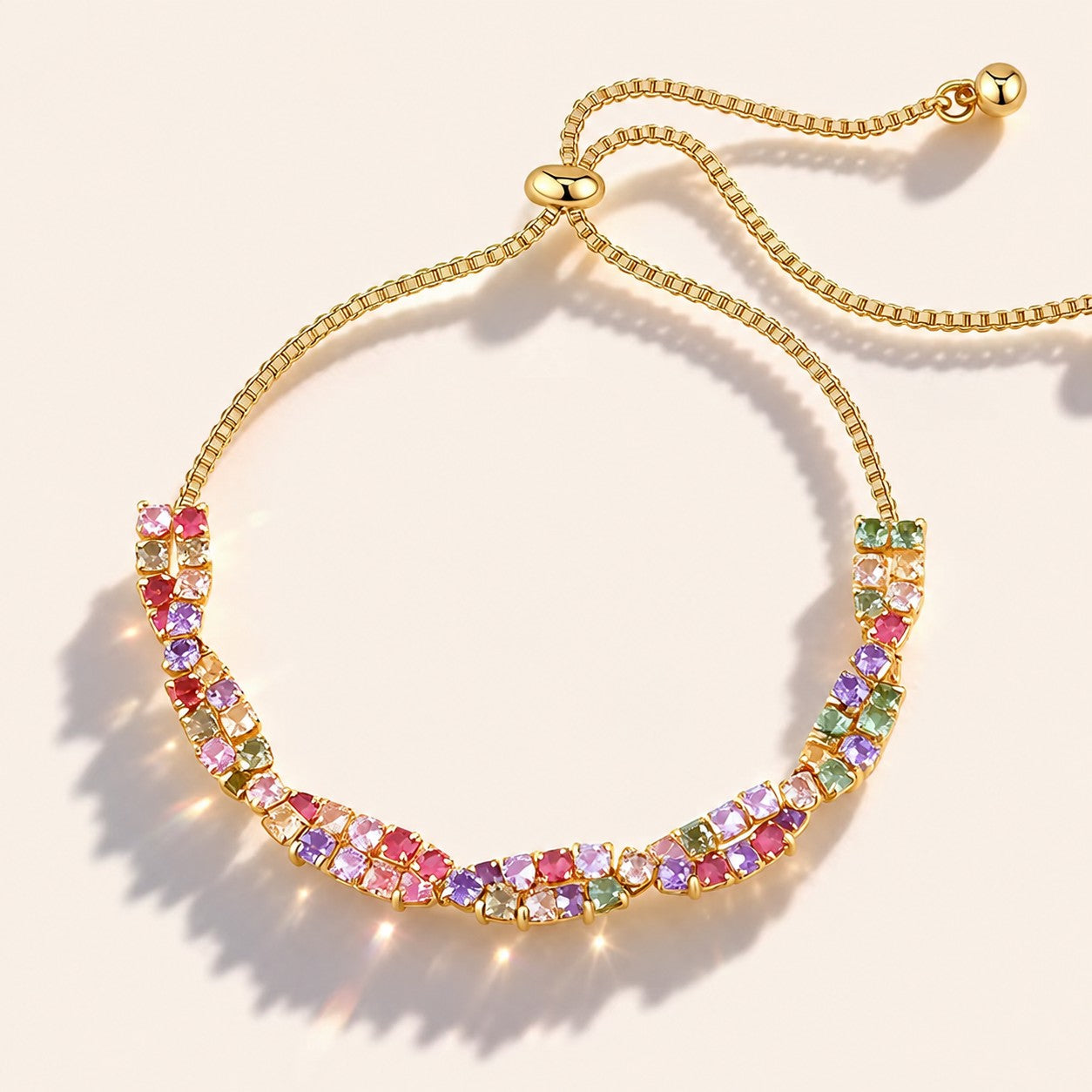 Rainbow multi-colored cubic zirconia twisted gold slider bracelet with bolo toggle on cream background