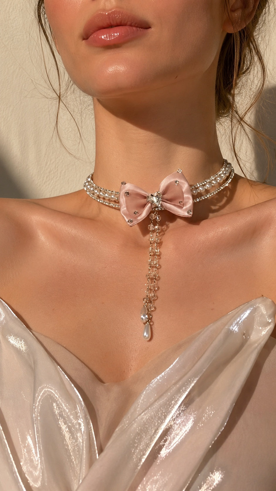 Model wearing coquette aesthetic pink bow pearl necklace with crystal tassels and silk corset