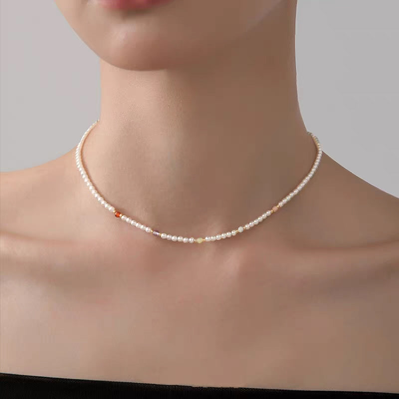 Close-up of model showcasing rainbow beaded pearl necklace resting along collarbone