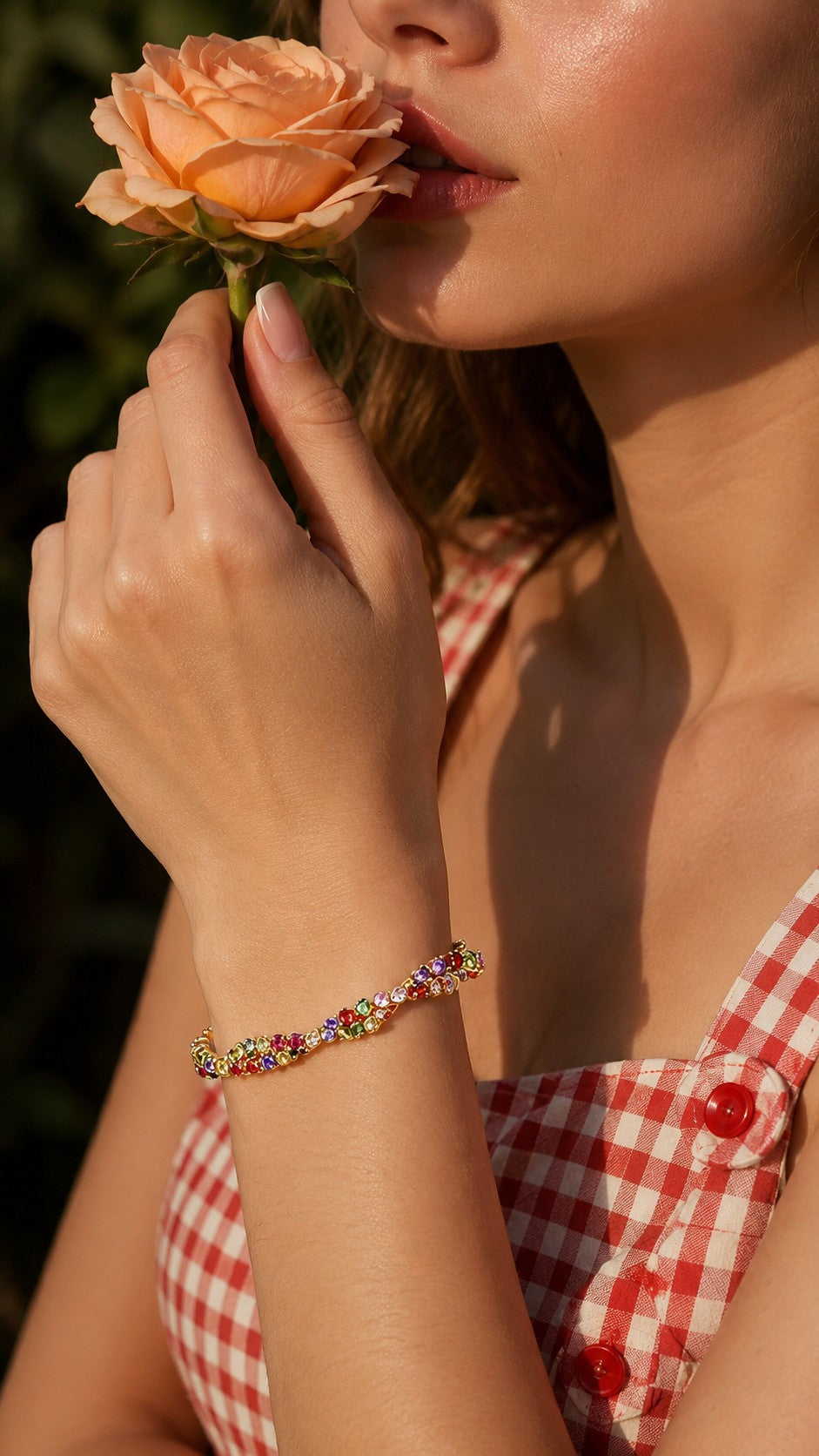 Model wearing colorful dopamine rainbow cubic zirconia adjustable gold bracelet holding a peach rose