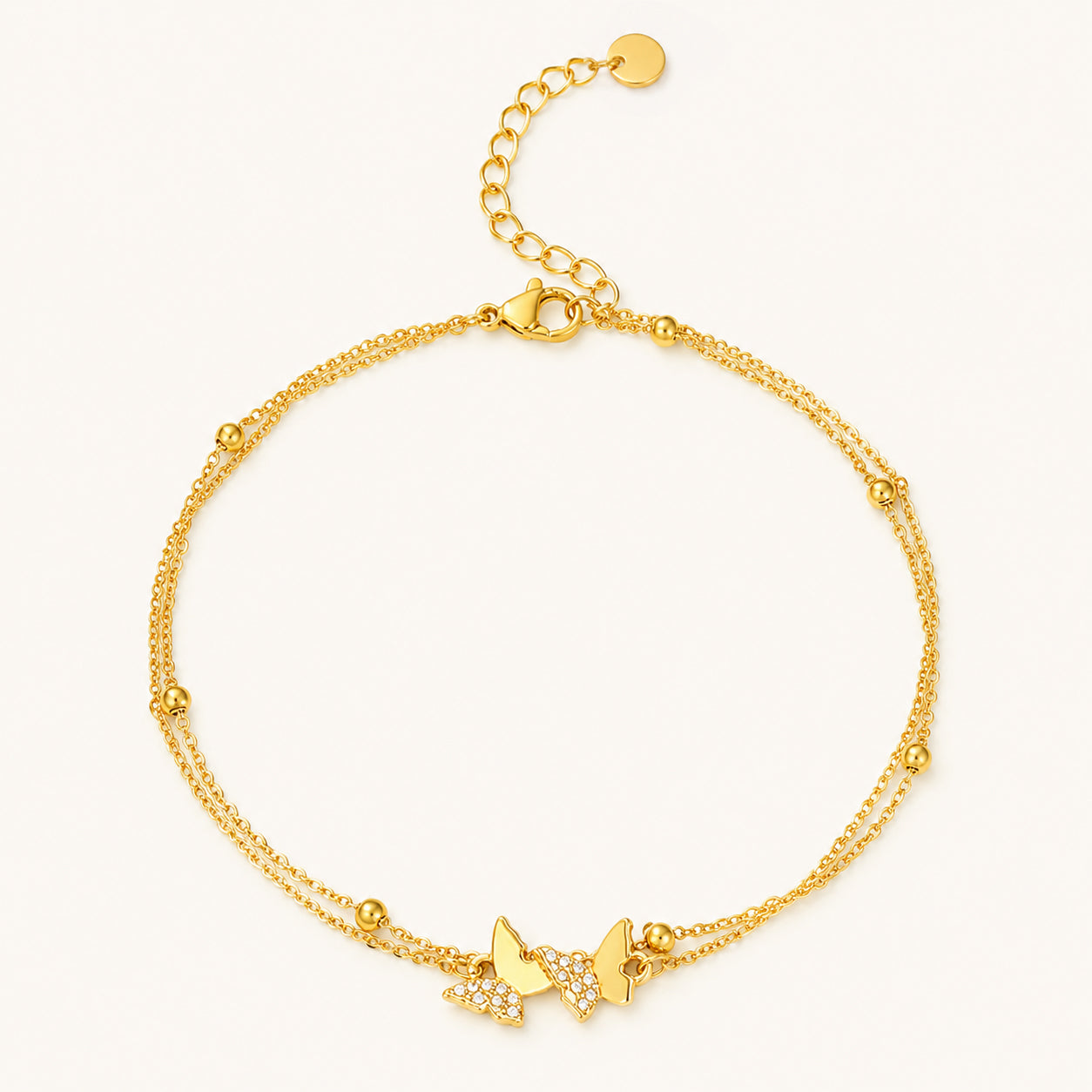 Minimalist double-layer gold-tone anklet featuring sparkling zirconia butterflies on a clean white background.