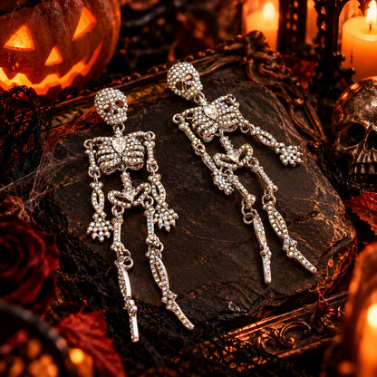 Silver crystal skeleton drop earrings surrounded by Halloween candles and spiderwebs