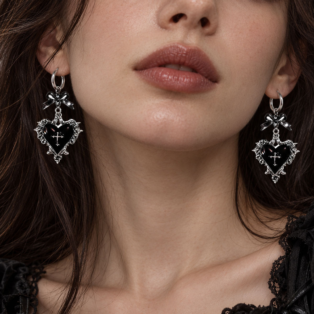 Close-up of model wearing gothic silver thorn rose frame red heart cross hoop earrings