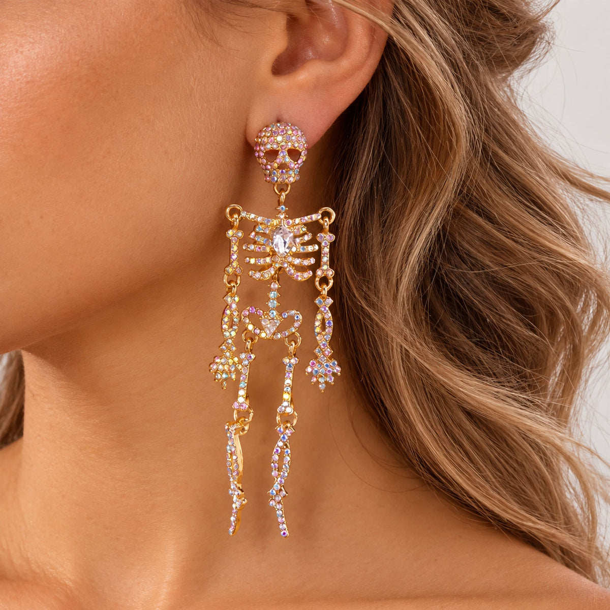 Model wearing long sparkling gold skeleton drop earrings for Halloween party look