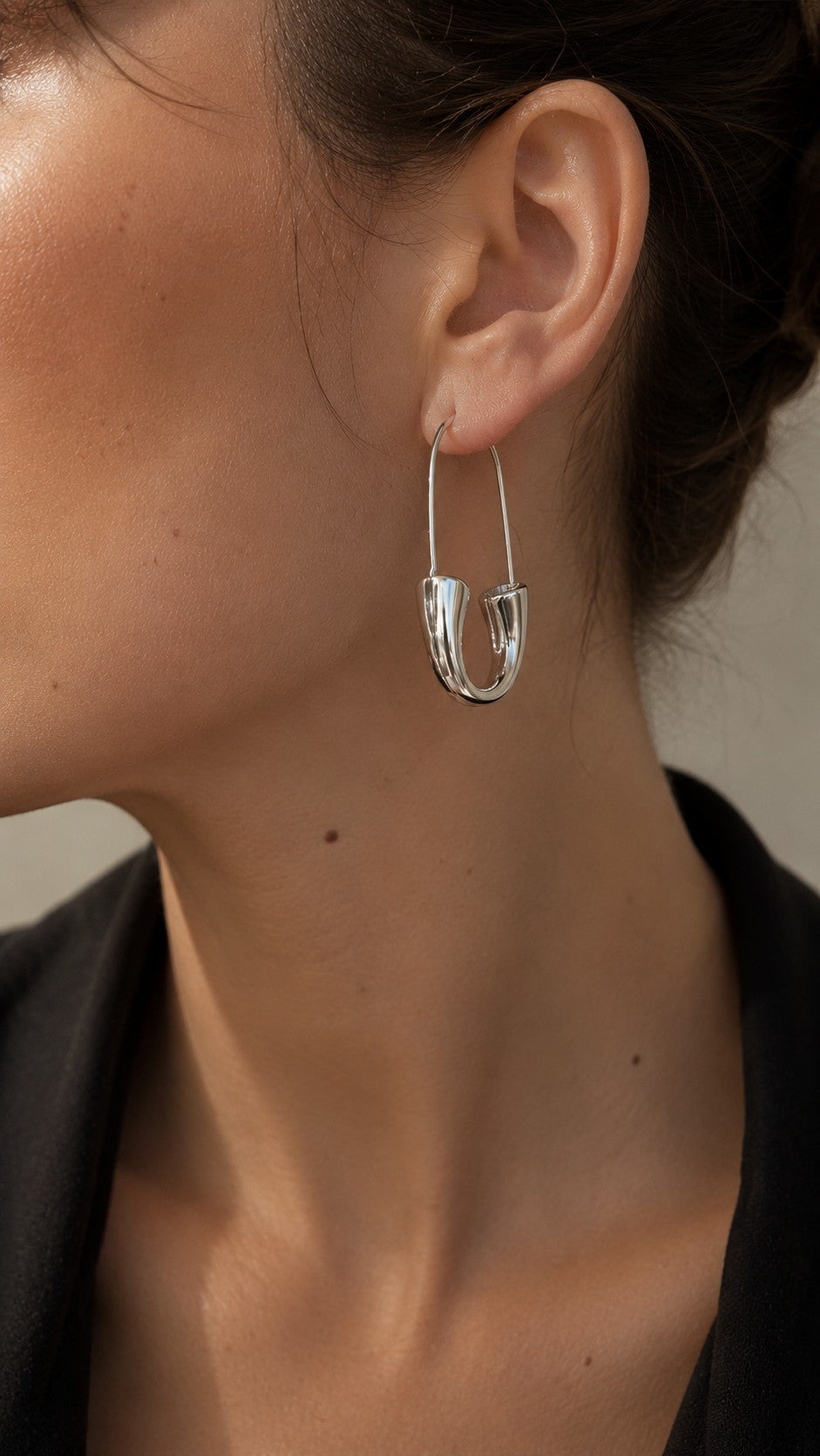 Close up of model wearing edgy minimalist silver safety pin geometric hoop earrings