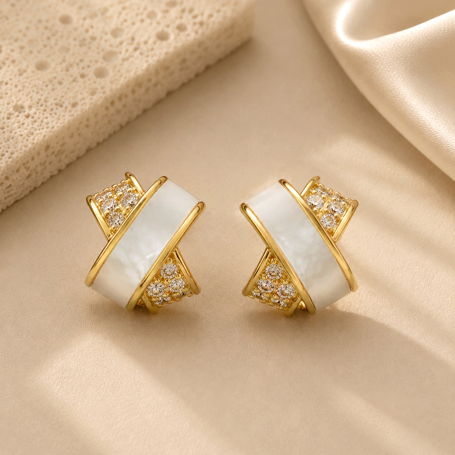 Elegant gold-tone criss-cross stud earrings featuring sparkling zirconia details.